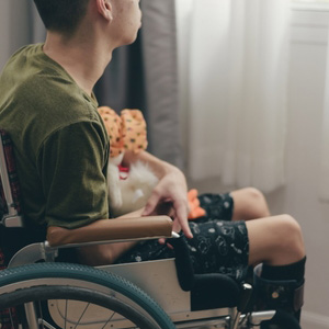 A young person in a wheelchair looking out a window, illustrating SSI for children.
