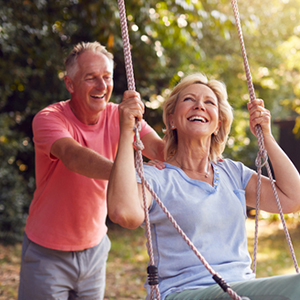 An active senior couple on a swing, illustrating early retirement benefits.