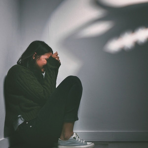 A person sitting on the floor in distress, representing an anxiety disorder claim.