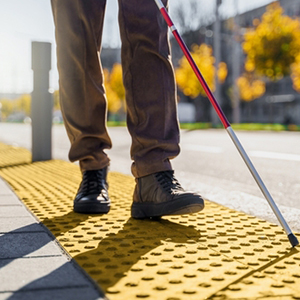 A person with a white cane walking on a tactile paving surface for SSI disability.