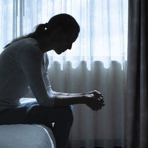 Silhouette of a person sitting alone in the dark, representing depression symptoms.