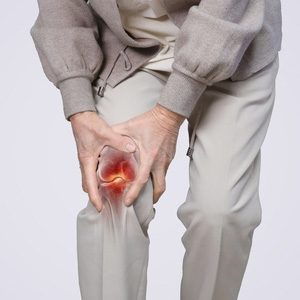 Close-up of a person holding a painful, inflamed knee joint with a red highlight.