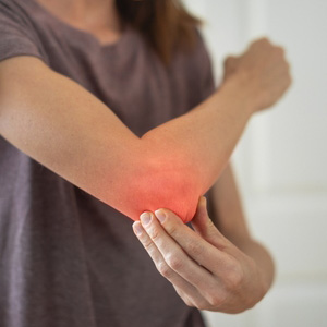 A person holding an inflamed, painful elbow joint highlighted with a red glow.