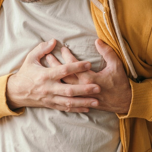 A person clutching their chest to represent chronic lung and heart pressure.