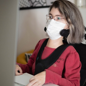 A young woman in a wheelchair using a laptop, representing muscular dystrophy benefits.