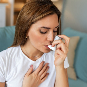 A woman using a rescue inhaler, representing asthma-related disability criteria.