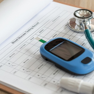 A glucose monitor and stethoscope on medical forms for a diabetes disability claim.