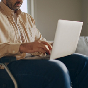 A person using a laptop while experiencing hip pain, representing joint disability.