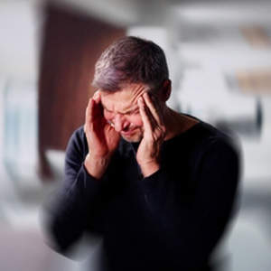 A person holding their head in pain, representing stroke-related disability symptoms.