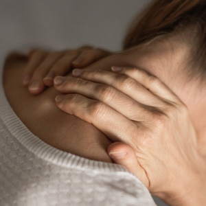 Close-up of a person holding their neck in pain, representing cervical spine disability.