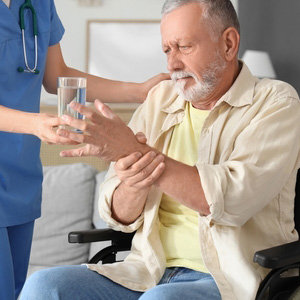 A caregiver assisting an elderly man with tremors to represent Parkinson's disability.